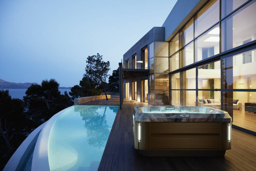 Steaming hot tub next to pool by the house